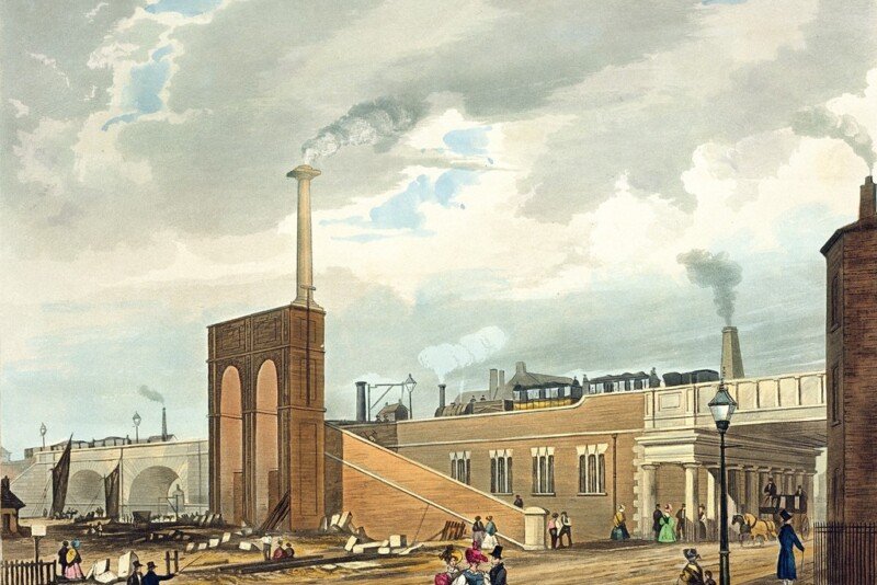 Cuarta parada: Liverpool. El día en que nació la era del ferrocarril 4 Colorized historical illustration of an early steam train entering Manchester across Water Street in 1831, with passengers and pedestrians in the foreground.